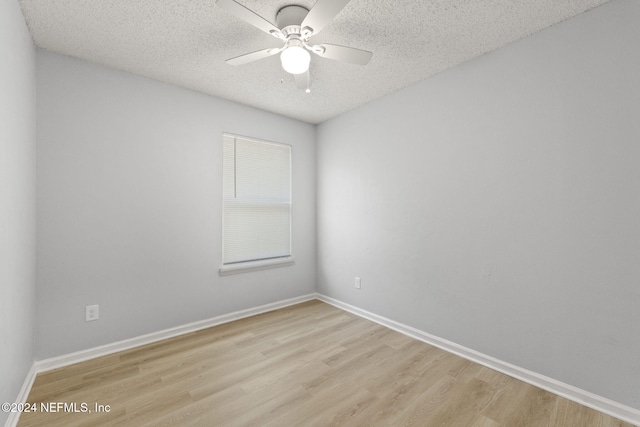 empty room with ceiling fan, light hardwood / wood-style floors, and a textured ceiling