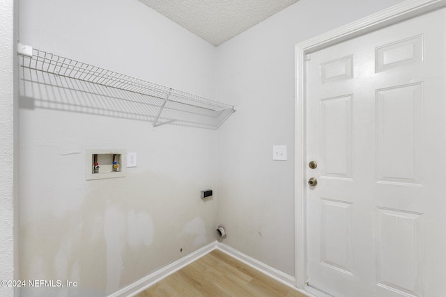 laundry room with hookup for an electric dryer, hookup for a washing machine, a textured ceiling, and hardwood / wood-style flooring