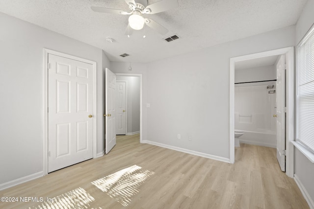 unfurnished bedroom with a textured ceiling, light hardwood / wood-style flooring, ensuite bath, and ceiling fan