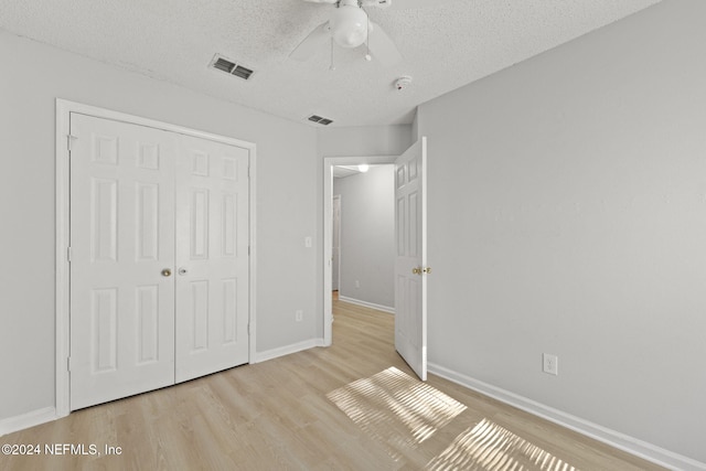 unfurnished bedroom with a closet, ceiling fan, light hardwood / wood-style flooring, and a textured ceiling