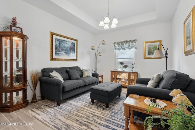 living room with a notable chandelier, light hardwood / wood-style floors, and a raised ceiling