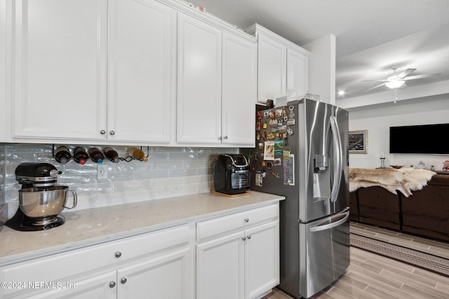 kitchen featuring tasteful backsplash, light stone counters, light hardwood / wood-style flooring, white cabinets, and stainless steel fridge with ice dispenser