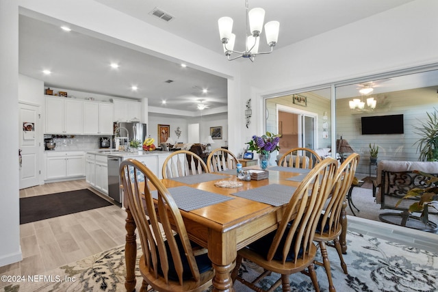 dining space with light hardwood / wood-style floors and a notable chandelier