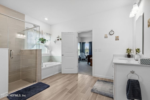 bathroom featuring plus walk in shower, vanity, hardwood / wood-style flooring, and a wealth of natural light