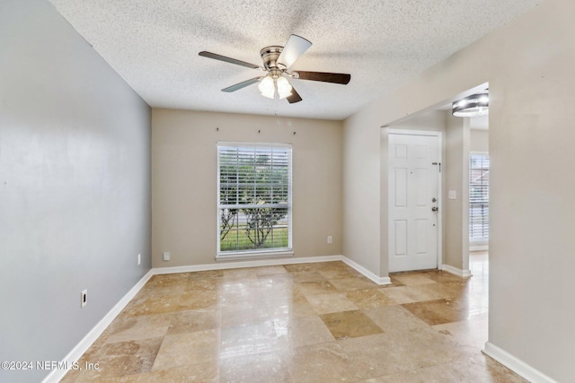 empty room with a textured ceiling and ceiling fan