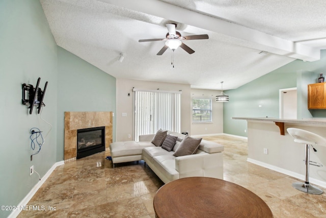 living room featuring ceiling fan, a fireplace, lofted ceiling with beams, and a textured ceiling