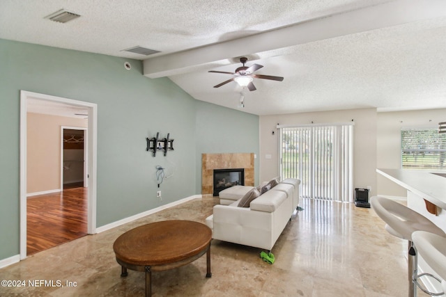 living room with a tile fireplace, ceiling fan, vaulted ceiling with beams, light hardwood / wood-style flooring, and a textured ceiling