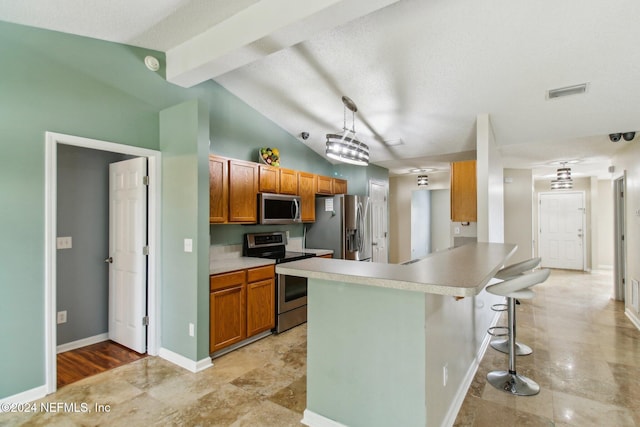 kitchen featuring hanging light fixtures, lofted ceiling with beams, a kitchen bar, appliances with stainless steel finishes, and light wood-type flooring