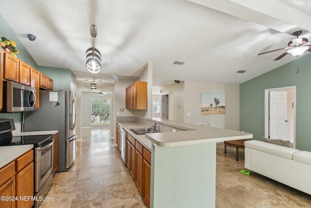 kitchen with lofted ceiling, sink, a textured ceiling, appliances with stainless steel finishes, and kitchen peninsula