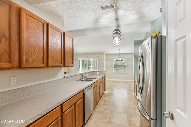 kitchen with pendant lighting, sink, stainless steel appliances, and a textured ceiling