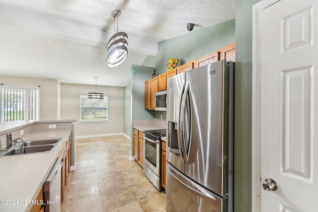 kitchen featuring pendant lighting, sink, a textured ceiling, and appliances with stainless steel finishes