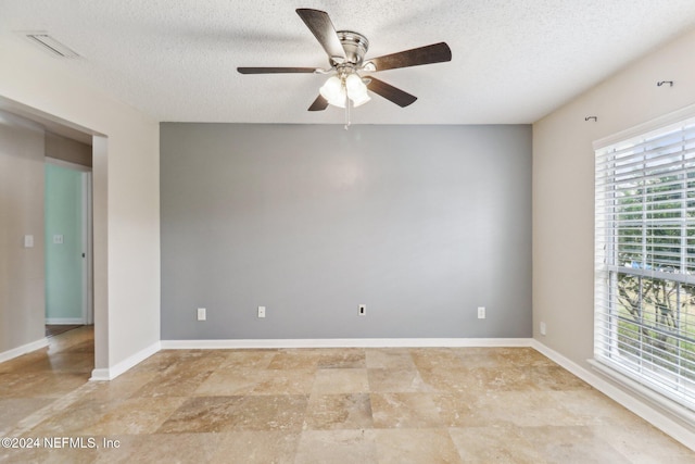 empty room with a textured ceiling, ceiling fan, and a healthy amount of sunlight