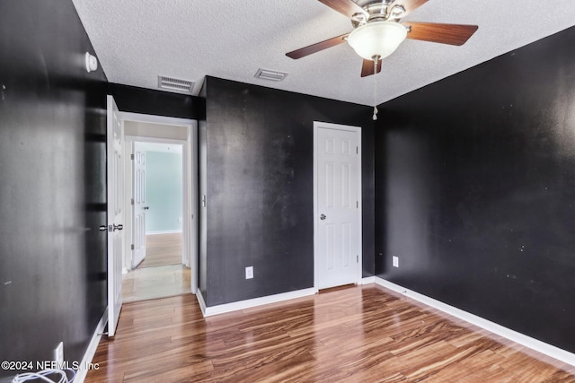 unfurnished bedroom with ceiling fan, hardwood / wood-style floors, and a textured ceiling