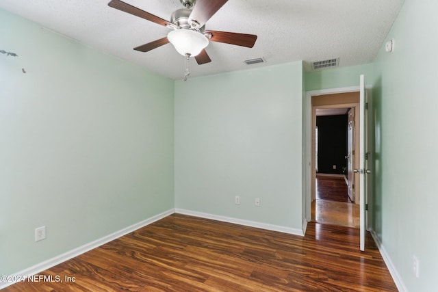 empty room with a textured ceiling, dark hardwood / wood-style flooring, and ceiling fan