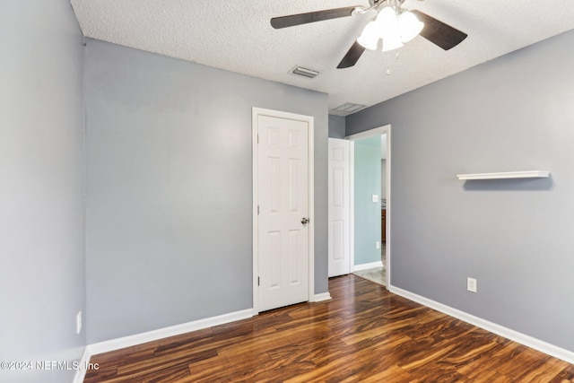 unfurnished bedroom with a textured ceiling, ceiling fan, and dark hardwood / wood-style floors