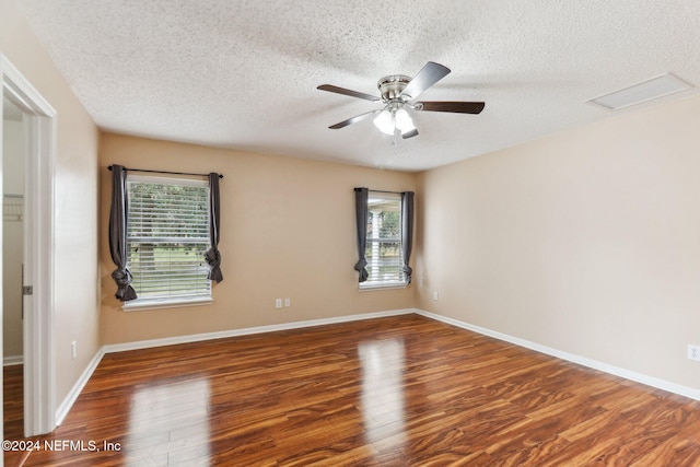 unfurnished room featuring a textured ceiling, plenty of natural light, ceiling fan, and dark wood-type flooring