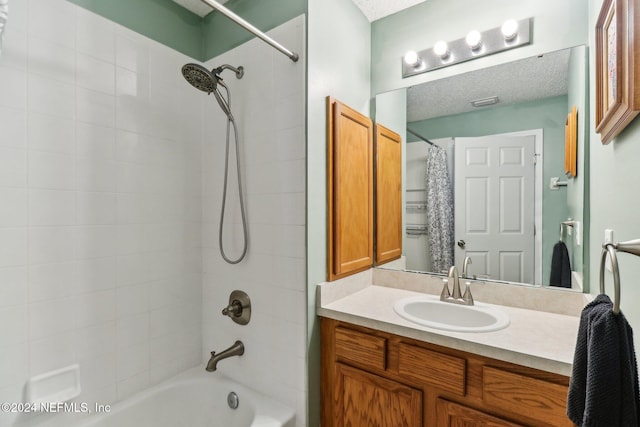 bathroom with vanity, shower / bathtub combination with curtain, and a textured ceiling