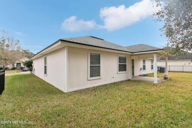 rear view of property featuring central AC unit and a lawn