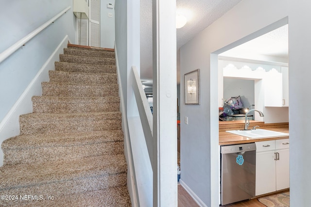 stairway with hardwood / wood-style floors, sink, and a textured ceiling