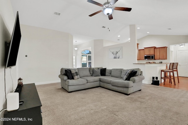 carpeted living room with ceiling fan and vaulted ceiling