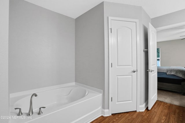 bathroom with hardwood / wood-style floors, ceiling fan, and a bathing tub