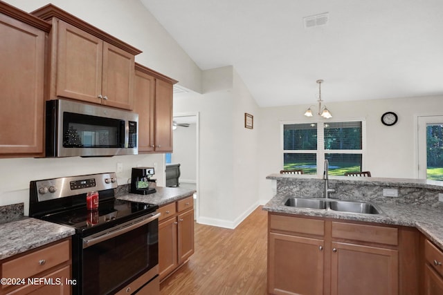 kitchen featuring sink, stainless steel appliances, light stone counters, vaulted ceiling, and light wood-type flooring