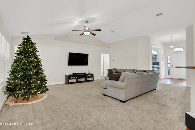 living room with ceiling fan, plenty of natural light, light colored carpet, and lofted ceiling