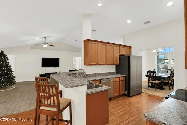 kitchen featuring kitchen peninsula, light hardwood / wood-style flooring, stainless steel appliances, and vaulted ceiling