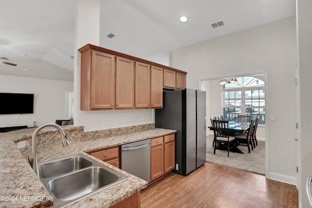 kitchen with appliances with stainless steel finishes, light wood-type flooring, light stone counters, ceiling fan with notable chandelier, and sink