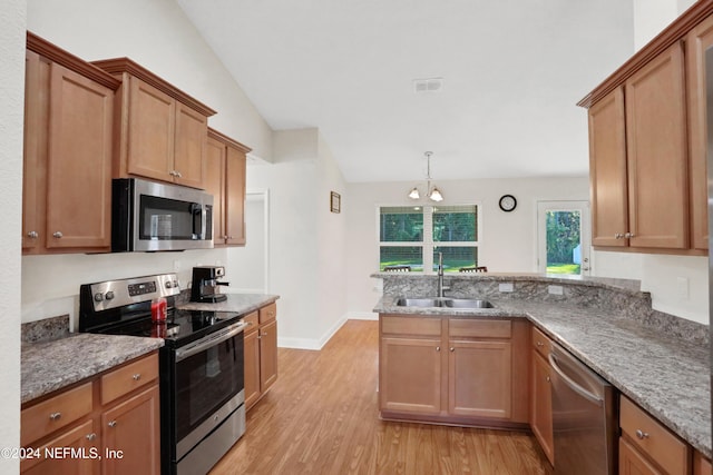 kitchen with sink, stainless steel appliances, pendant lighting, vaulted ceiling, and light wood-type flooring