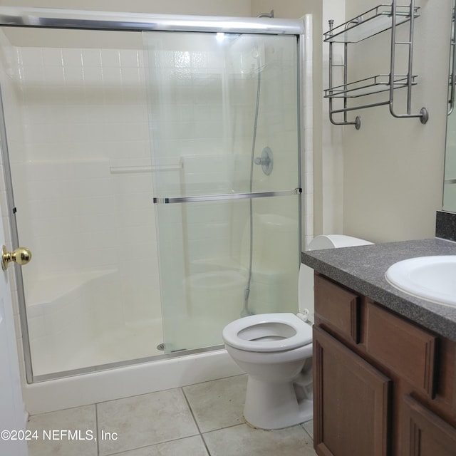 bathroom with tile patterned flooring, vanity, a shower with shower door, and toilet