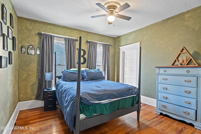 bedroom featuring ceiling fan, dark wood-type flooring, and a textured ceiling