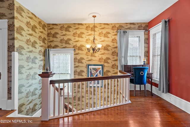 hall featuring wood-type flooring and a notable chandelier