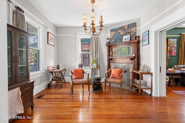 living area featuring a chandelier, wood-type flooring, and a stone fireplace