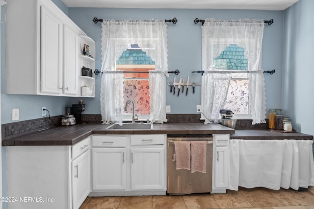 kitchen with white cabinetry, sink, stainless steel dishwasher, tile countertops, and light tile patterned flooring