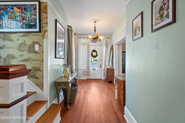 hall with hardwood / wood-style floors and a notable chandelier