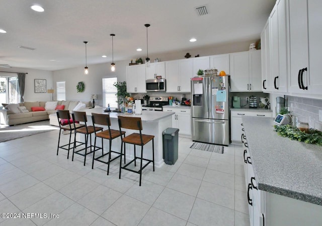 kitchen featuring a center island, white cabinets, a kitchen breakfast bar, hanging light fixtures, and appliances with stainless steel finishes