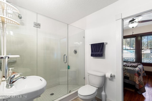 bathroom featuring ceiling fan, sink, wood-type flooring, a textured ceiling, and an enclosed shower