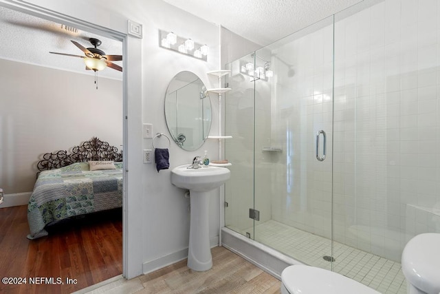 bathroom featuring hardwood / wood-style floors, ceiling fan, toilet, a textured ceiling, and an enclosed shower