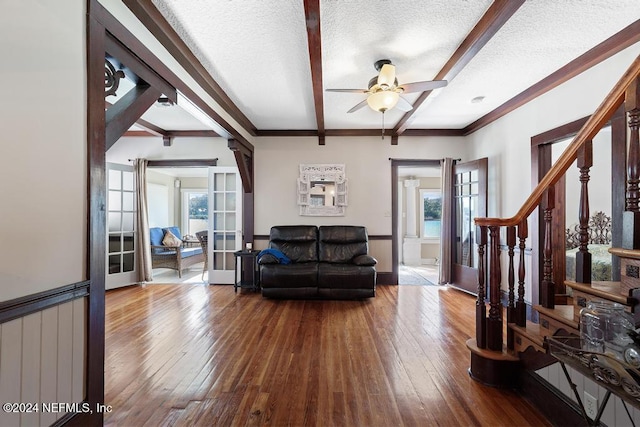 living room featuring beam ceiling, a textured ceiling, and hardwood / wood-style flooring