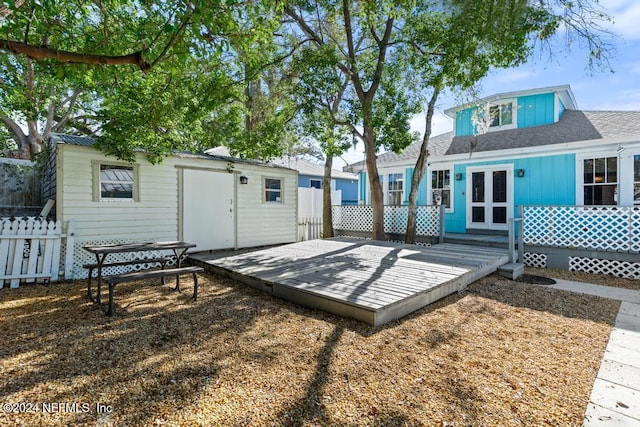 rear view of house featuring an outbuilding, a wooden deck, and french doors