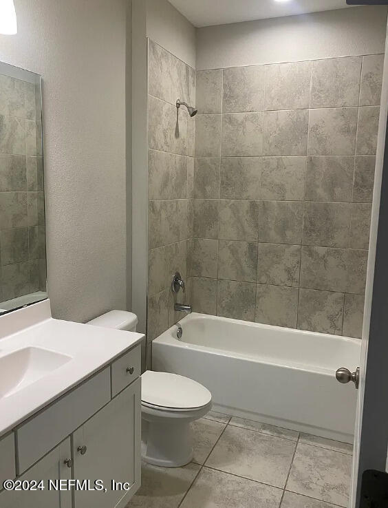 full bathroom featuring tile patterned flooring, tiled shower / bath combo, toilet, and vanity