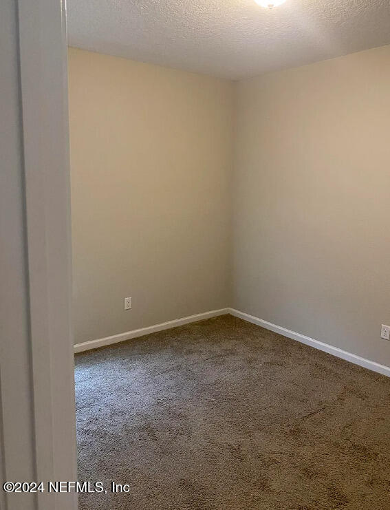 carpeted spare room with a textured ceiling