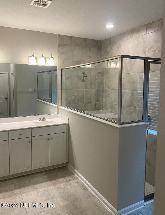 bathroom with vanity and tiled shower