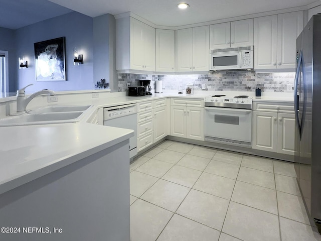 kitchen with sink, kitchen peninsula, white appliances, decorative backsplash, and white cabinets