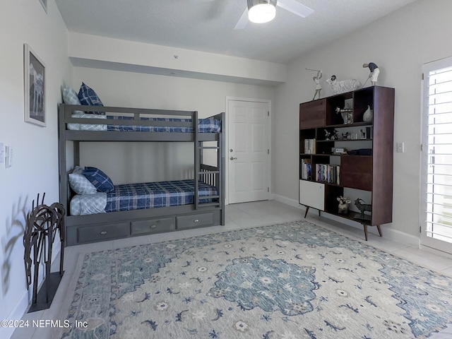 tiled bedroom with ceiling fan and a textured ceiling