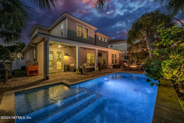 pool at dusk featuring a patio area and ceiling fan