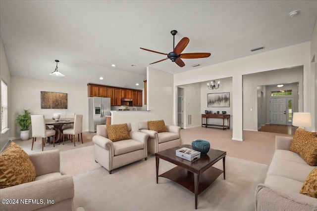 living room with ceiling fan with notable chandelier and light colored carpet