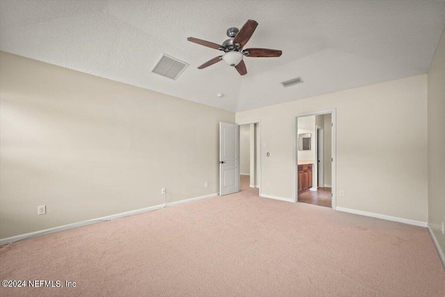 unfurnished bedroom featuring carpet flooring, a textured ceiling, ensuite bath, and ceiling fan