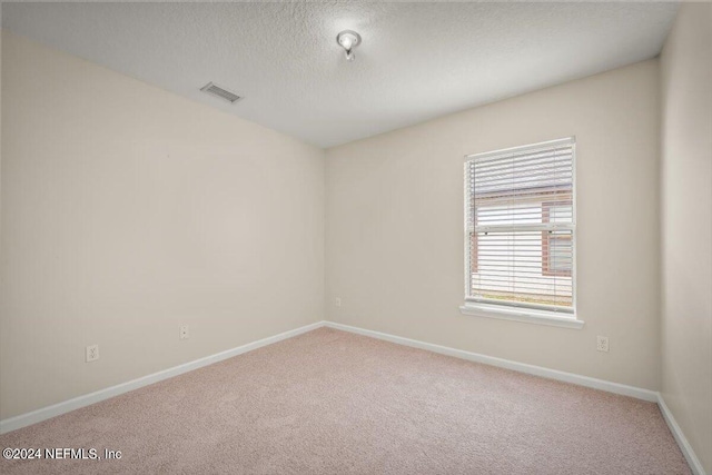 carpeted empty room with a textured ceiling